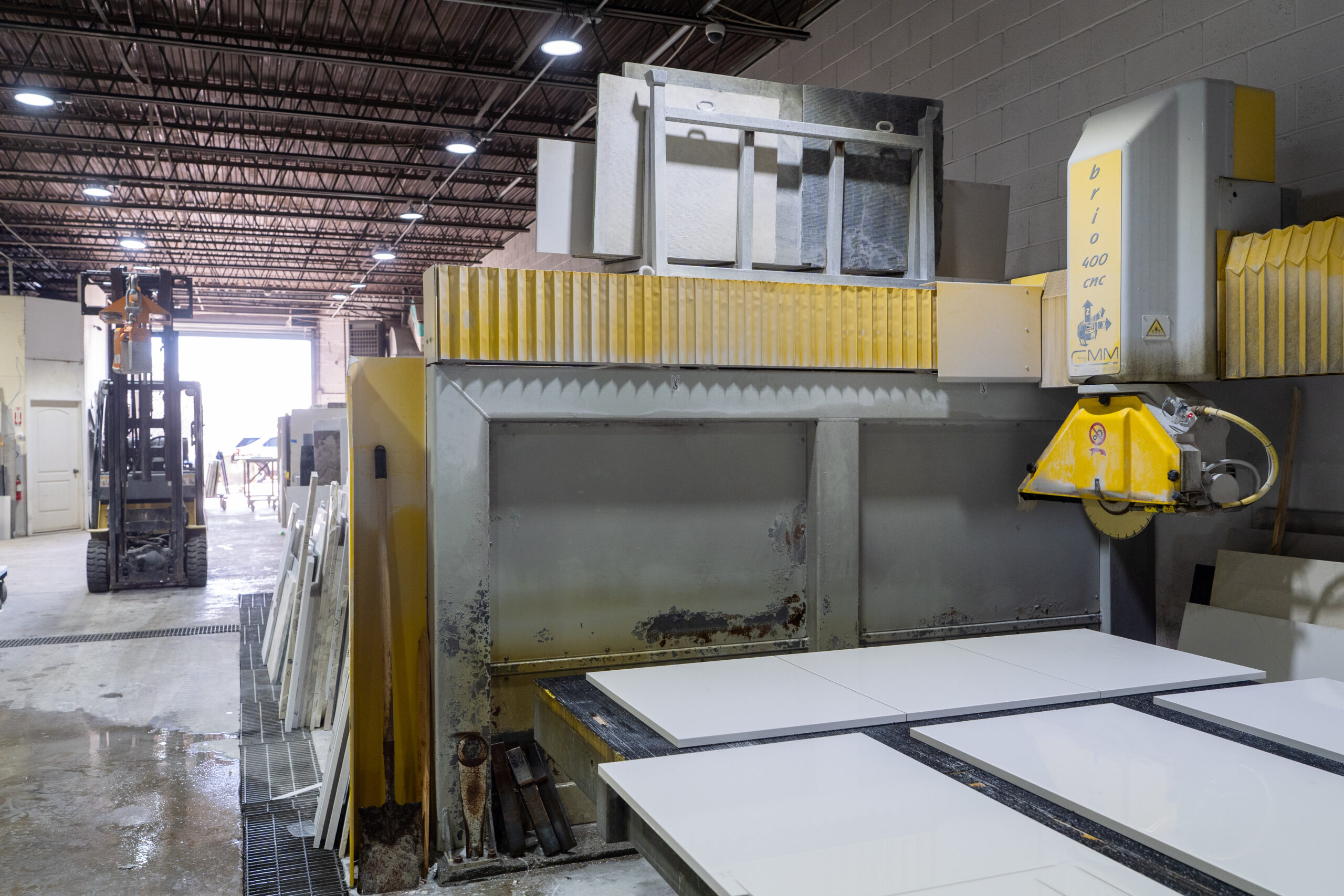 Stone slabs being cut by a stone cutting machine in a fabrication workshop.