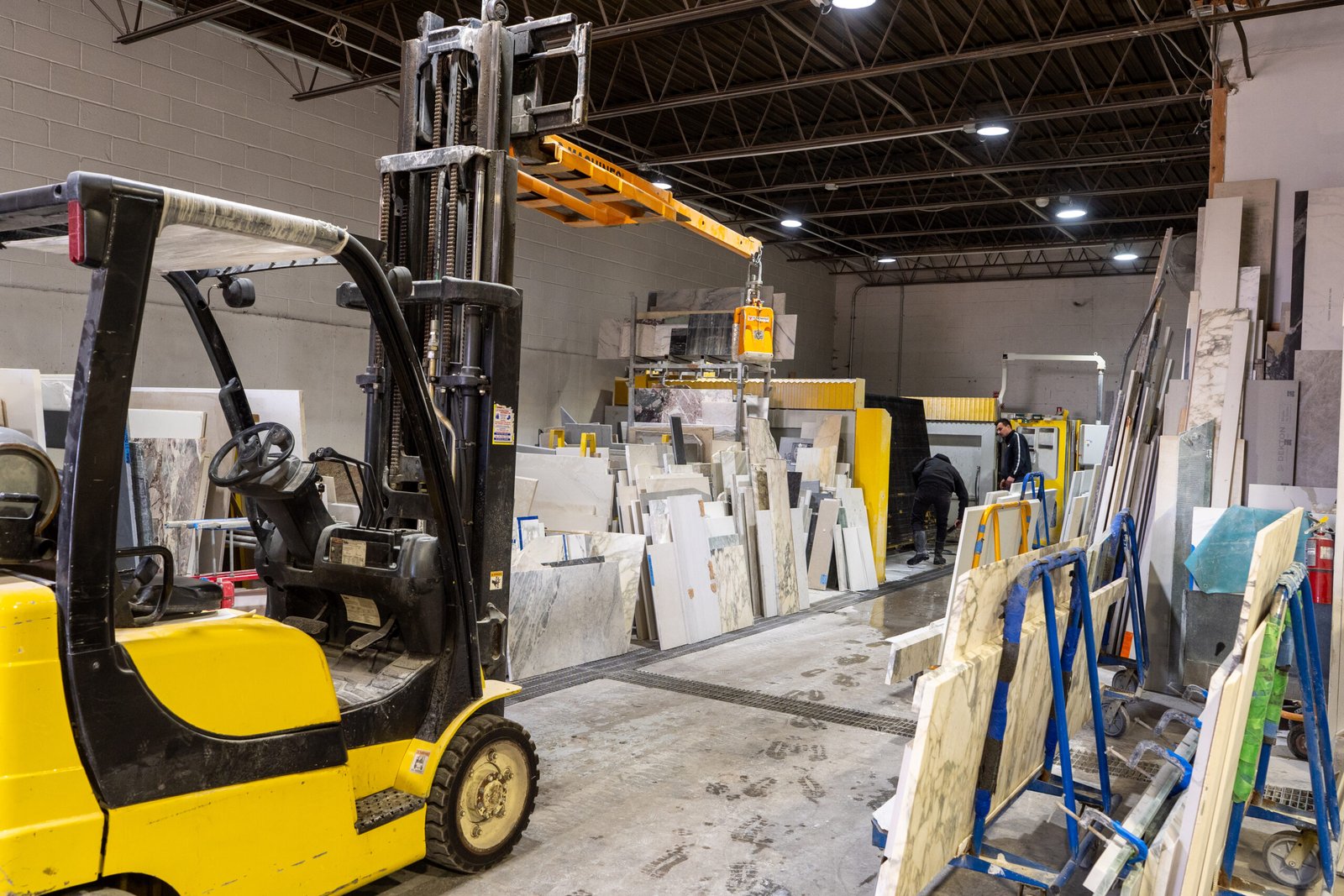 Stone fabrication warehouse with marble and granite slabs and workers